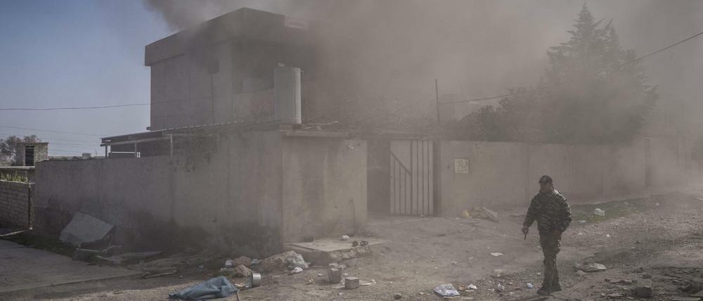 Ein Mann geht in Mossul, Irak, in der Nähe des Flughafens an einem in Brand gesetzten Haus vorbei.