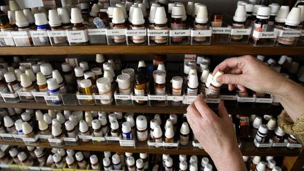 Blick in einen Schrank auf Fläschchen mit homöopathischen Präparaten in der Praxis einer Heilpraktikerin.
