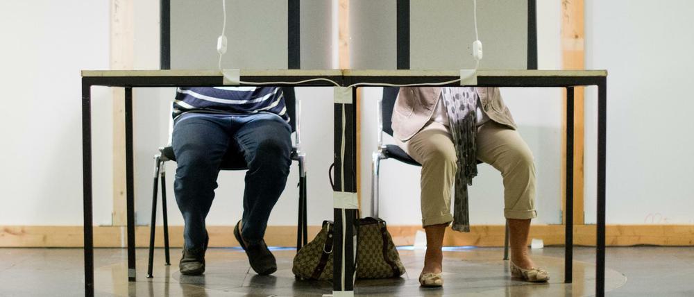 Ein Mann und eine Frau sitzen in einem Wahlraum in Niedersachsen.
