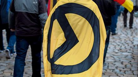 Ein Mann mit einer Fahne mit Logo der Identitären Bewegung bei einer Kundgebung (Archivbild)