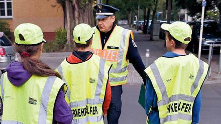 Ein Polizist mit Schülerlotsen - häufig ersetzen Polizisten diese mittlerweile