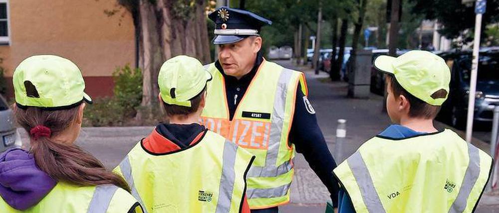 Ein Polizist mit Schülerlotsen - häufig ersetzen Polizisten diese mittlerweile