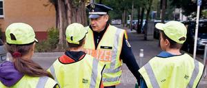Ein Polizist mit Schülerlotsen - häufig ersetzen Polizisten diese mittlerweile