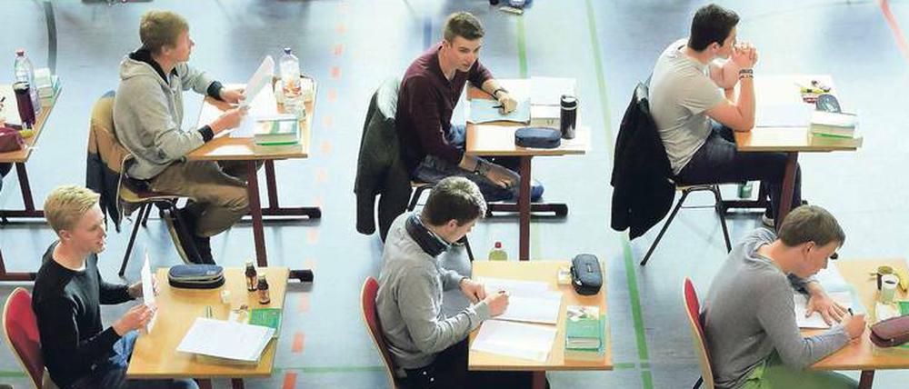 Schüler sitzen bei einer Abiturklausur an Einzeltischen.