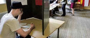 Ein Wahlberechtigter sitzt in einem Wahllokal in Berlin in einer Wahlkabine und füllt seinen Wahlzettel aus.