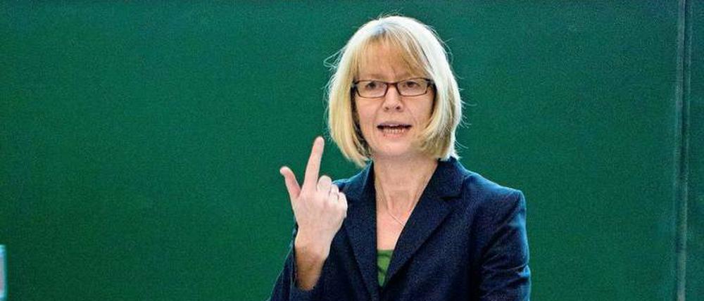 Eine Professorin steht im Hörsaal vor Studierenden und erklärt einen Versuch aus der Physik.