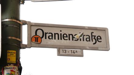 Ein Straßenschild der Oranienstraße. Radfahrer sind gefährdet, Busse fahren langsam und Fußgänger kommen nicht rüber.