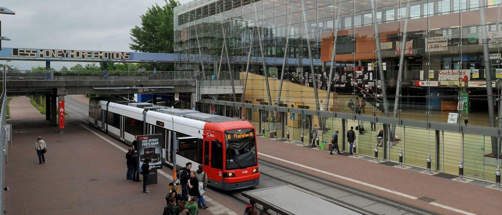 Eine Straßenbahn fährt vor einem Universitätsgebäude fest.