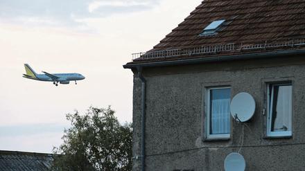 Ein Passagierflugzeug befindet sich im Landeanflug über den Dächern von Häusern im Ort Sielow unweit des Flughafens Schönefeld.