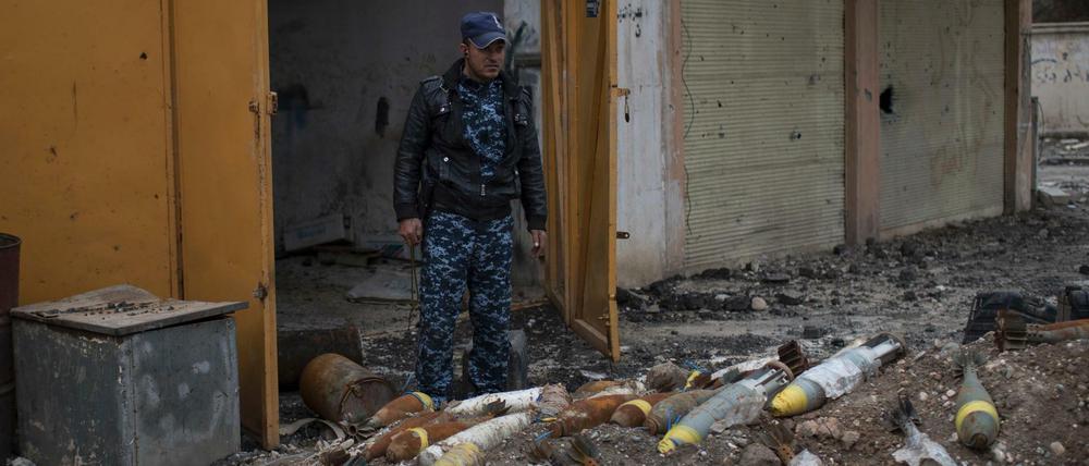 Ein Polizist der irakischen Bundespolizei steht am Mittwoch neben Mörsergranaten im Westen von Mossul (Irak). Die Munition wurde von Kämpfern der Terrormiliz Islamischer Staat zurückgelassen.
