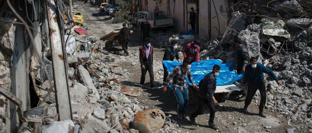 Ehemalige Bewohner der zerstörten Häuser eines Viertels von Mossul, Irak, transportieren am 24.03.2017 Tote die aus den Trümmern geborgen wurden, ab.