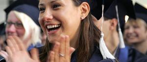 Absolventinnen und Absolventen einer Uni mit Doktorhüten, eine Frau klatscht in die Hände.