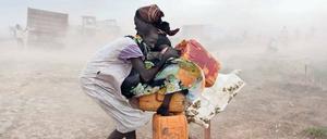 Im UN-Flüchtlingslager Malakal im Südsudan versuchen zwei Mädchen, sich vor einem Sandsturm in Sicherheit zu bringen.