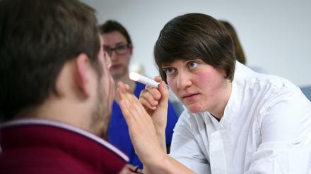 Eine Medizinstudentin blickt einem Patienten ins Auge.