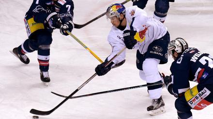 Münchens Frank Mauer (M) versucht, den Puck vorbei an Berlins Frank Hördler (l), Kyle Wilson (r) und Bruno Gervais zu spielen. 