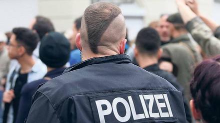 Deeskalationsfrisur. Ein Polizist einer Hundertschaft mit punkigem Kurzhaarschnitt beobachtet Demoteilnehmer 2013 in Kreuzberg.