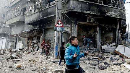 Kinder laufen am durch den schwer beschädigten Bezirk Bustan al-Qasr in Ost-Aleppo. 