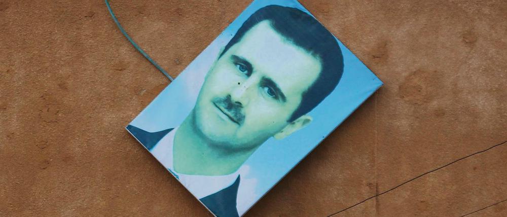 Das Bild von Syrischen Präsident Bashar al-Assad wird von einer Wand in Ariha gestoßen.