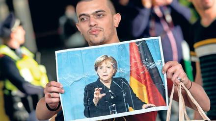 Herzdame. Ein Flüchtling hält bei seiner Ankunft in München im Jahr 2015 ein Foto von Angela Merkel in den Händen.