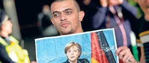 Herzdame. Ein Flüchtling hält bei seiner Ankunft in München im Jahr 2015 ein Foto von Angela Merkel in den Händen.