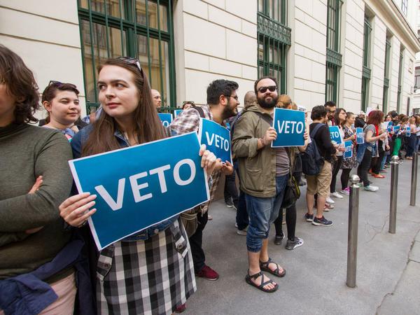 Menschen stehen in einer Kette und halten Schilder mit der Aufschrift Veto hoch.