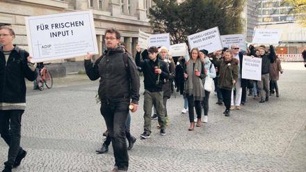 Studierende tragen Plakate und Grableuchten über einen Uni-Campus.