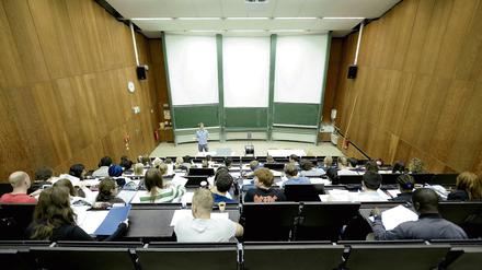Ein junger Mann steht vor Studierenden im Hörsaal und spricht zu ihnen.