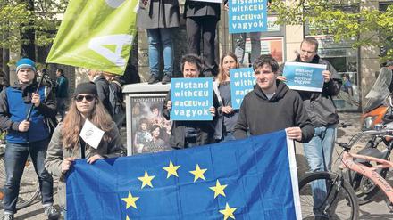 Jungen Menschen stehen am Rand einer Straße und halten Schilder mit der Aufschrift I stand with CEU hoch.