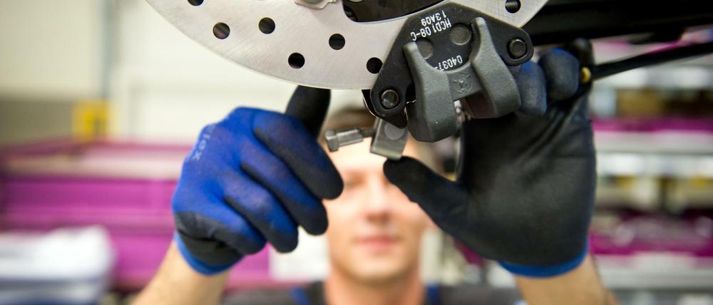 Ein Mann arbeitet im BMW-Motorradwerk in Berlin in der Produktion. Die Bundesregierung hebt ihre Prognose für das Wirtschaftswachstum für dieses Jahr leicht an.