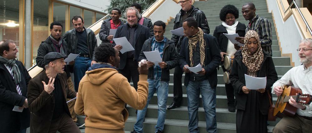 Sängerinnen und Sänger aus verschiedenen Herkunftsländern stehen auf einer Treppe und singen Lieder vom Blatt.