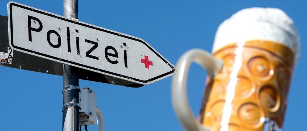 Eine Videokamera und ein Schild mit der Aufschrift "Polizei" hängen auf dem Münchner Oktoberfestgelände. Im Hintergrund ist ein Bierkrug auf einem Festzelt zu sehen.