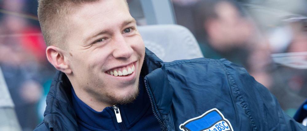 Berlins Mitchell Weiser sitzt lachend auf der Spielerbank.