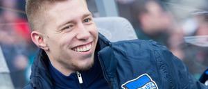 Berlins Mitchell Weiser sitzt lachend auf der Spielerbank.