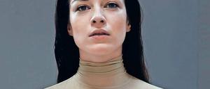 Ein Model trägt ein Oberteil aus Latex in Hautfarben.