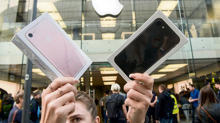 Eine Frau präsentiert zum Verkaufsstart des neuen iPhone 7 zwei Smartphones.