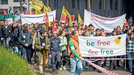 Studierende marschieren bei einer Demonstration durch eine Straße und halten Plakate hoch.