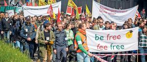 Studierende marschieren bei einer Demonstration durch eine Straße und halten Plakate hoch.