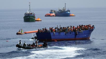 Marinesoldaten fahren mit einem Boot zu einem überfüllten Flüchtlingsboot auf dem Mittelmeer. 
