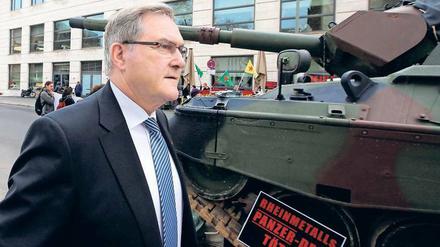 Frontwechsel. Franz Josef Jung spaziert vorbei an den Demonstranten mit ihrem ausgemusterten Panzer.
