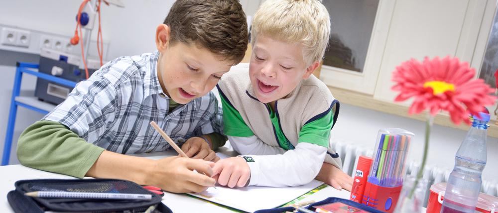 Gemeinsamer Unterricht. Schüler mit und ohne Down-Syndrom in einer Gemeinschaftsschule beim Malen.