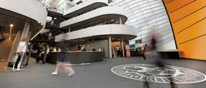 Studierende eilen durch das Foyer einer Universitätsbibliothek.