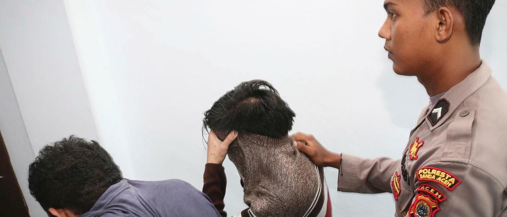 Ein Polizist führt zwei Männer in Banda Aceh (Indonesien) ab. Wegen ihrer Homosexualität sollen sie öffentlich ausgepeitscht werden.