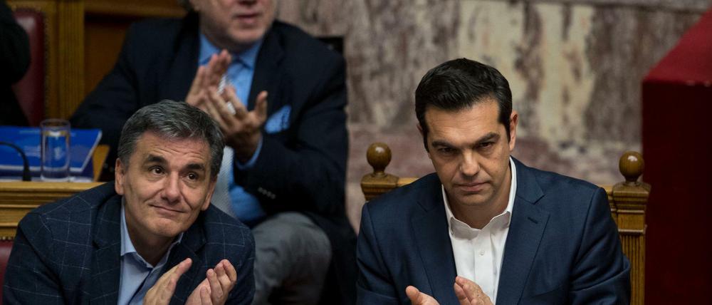 Der griechische Ministerpräsident Alexis Tsipras (r) und der griechische Finanzminister Efklidis Tsakalotos (l) applaudieren am Donnerstag im Parlament in Athen (Griechenland) während einer Parlamentssitzung.