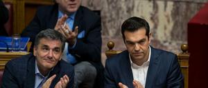 Der griechische Ministerpräsident Alexis Tsipras (r) und der griechische Finanzminister Efklidis Tsakalotos (l) applaudieren am Donnerstag im Parlament in Athen (Griechenland) während einer Parlamentssitzung.