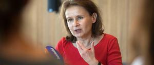 Eine Frau sitzt gestikulierend vor Mikrofonen.