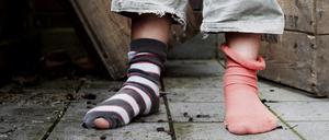 Ein zehn Jahre altes Mädchen steht in abgetragener Kleidung ohne Schuhe in einem Hinterhof.