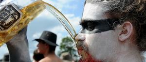 Ein Besucher im schleswig-holsteinischen Wacken auf dem Gelände des Heavy-Metal-Festivals mit einem Bier.