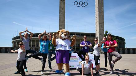 Das Turnfest-Maskottchen macht gemeinsam mit den freiwiligen Helfern Yoga Übungen.