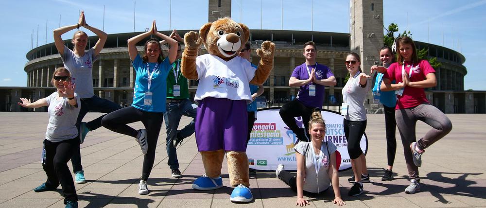 Das Turnfest-Maskottchen macht gemeinsam mit den freiwiligen Helfern Yoga Übungen.
