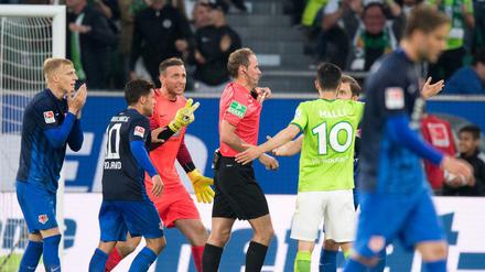 Schiedsrichter Stegemann wird nach einer Elfmeterentscheidung von den Spielern belagert.